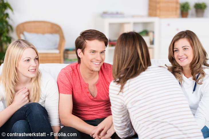 Junge Menschen sitzen auf einem Sofa und unterhalten sich miteinander