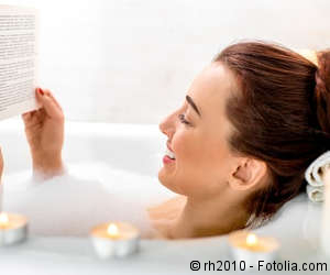 Frau liest in der Badewanne ein Buch