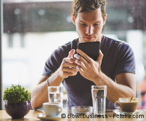 Junger Mann mit Smartphone im Café