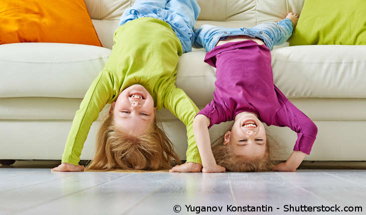 Zwei Kinder machen Handstand im Wohnzimmer