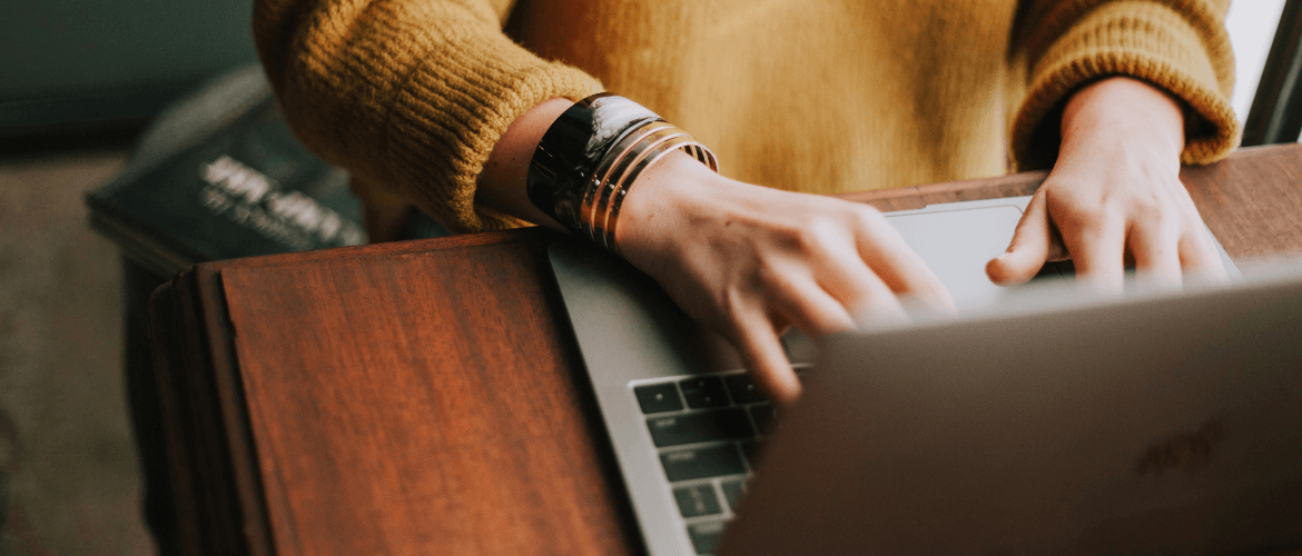 Person in gelbem Pullover arbeitet am Laptop – Symbol für die Vermietung möblierter Wohnungen.