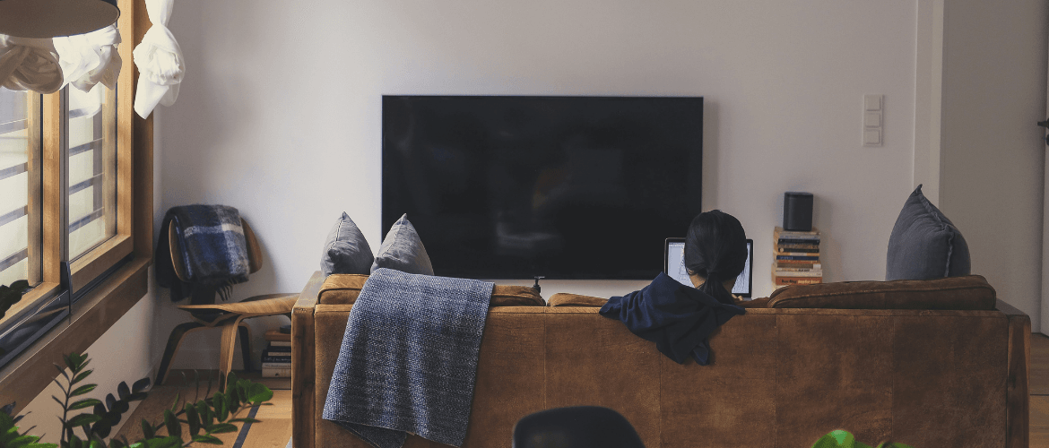 Person sitzt in modern eingerichteter Wohnung auf dem Sofa – Symbol für komfortables Wohnen auf Zeit.