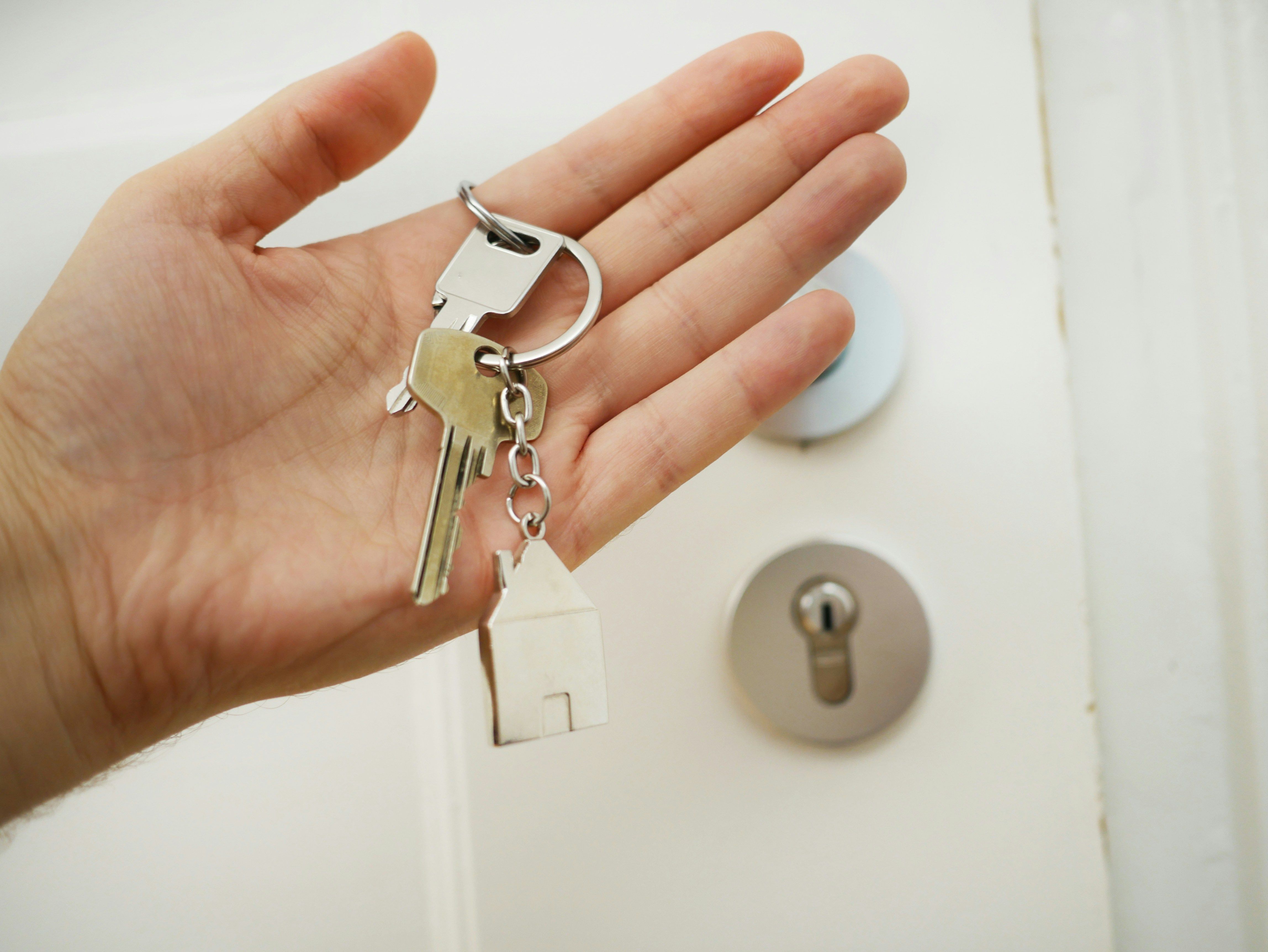 Hand holding apartment keys with house-shaped keychain – symbolizing temporary rental and short-term living.