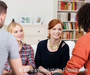  A group of four young people with different nationalities sitting together talking.