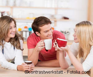 Three young people in the kitchen drinking coffee and talking 