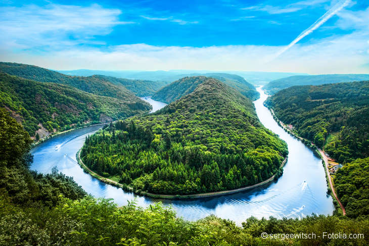 Blick auf Fluss der in U-Form fließt. Umgeben von grünen Wäldern.