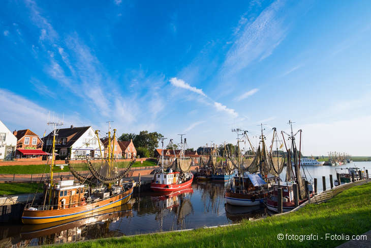 A river with colorful fishing boats. In the background there are northern buildings.