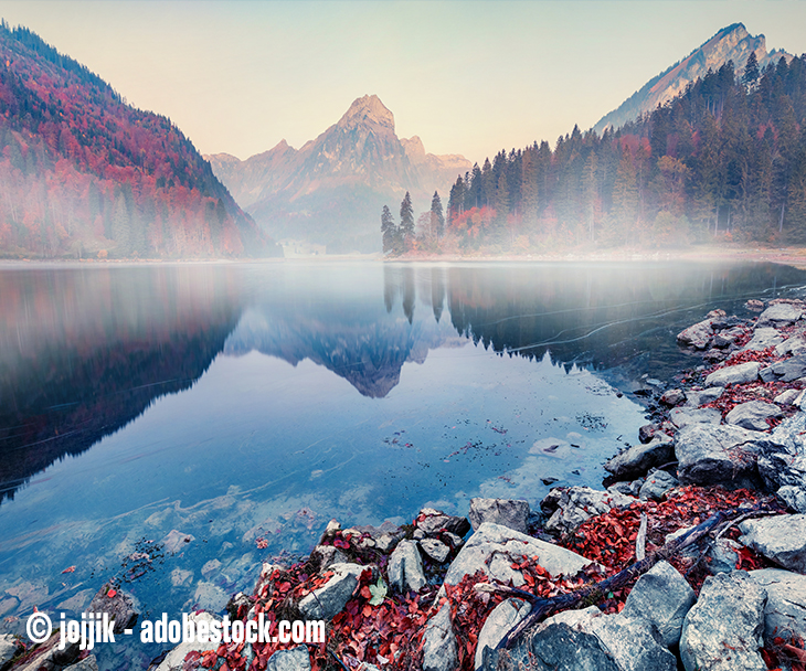 Der Glarner Obersee an einem Herbstmorgen mit buntgefärbten Wäldern im Hintergrund. 